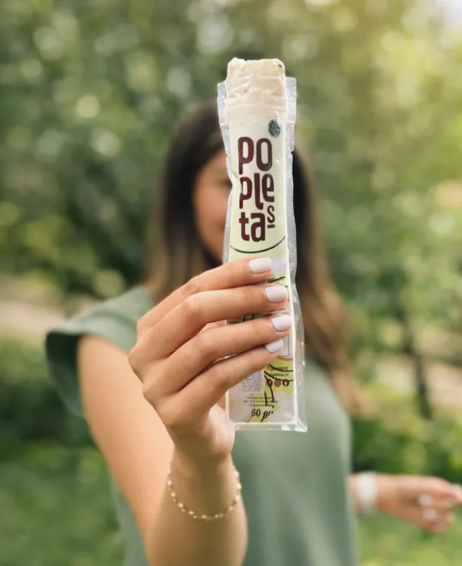 Mujer al aire libre muestra una paleta Popletas en su empaque individual transparente